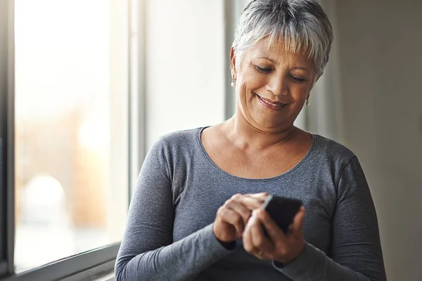 家庭で携帯電話 ソーシャルメディア モバイルアプリでウィンドウ タイピング シニア女性 幸せなモデルとスマートフォンを持つ老婦人 ネットワークとオンライン読書と電子メールと幸福 — ストック写真