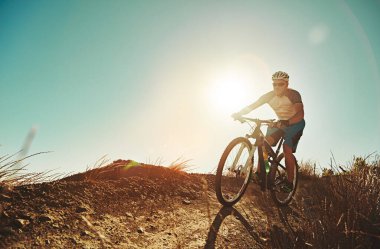 Dağ bisikletçiliği sana daha iyi bir egzersiz sağlıyor. Kırsalda bisiklet süren bir adam.