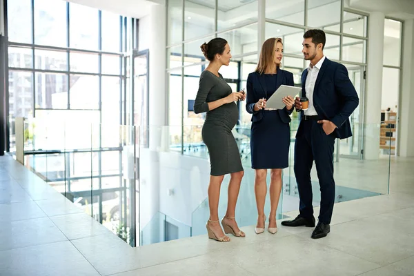 stock image Coming together is a beginning, working together is success. Full length shot of a group of young businesspeople standing together in a modern office and using a tablet