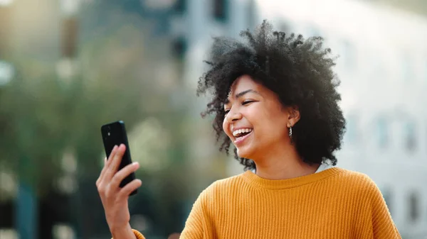 Video call, phone and black woman in city talking online, travel update and 5g communication or funny chat. Laughing gen z person or student on cellphone, mobile and live streaming for urban outdoor.