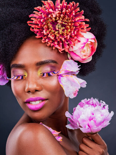 Flowers dont tell, they show. Studio shot of a beautiful young woman posing with flowers in her hair