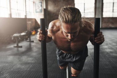 Güç ve azim gerektirir. Spor salonunda kızak iten kaslı genç bir adam.