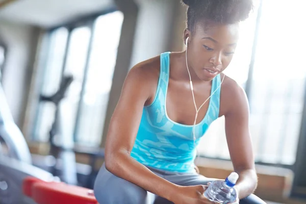 stock image Finding the will to carry on. a beautiful young woman listening to music and taking a water break at the gym