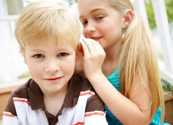 让我告诉你一个秘密一个可爱的小男孩听着姐姐在他耳边窃窃私语 — 图库照片