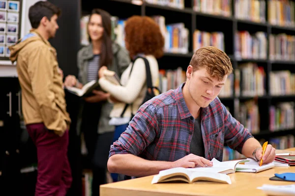 stock image Hes got good study habits. a male student studying in a university library with his peers in the background