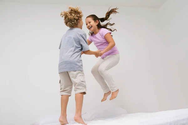 優しい笑顔 2人の小さな子供が一緒にベッドに飛び乗り — ストック写真