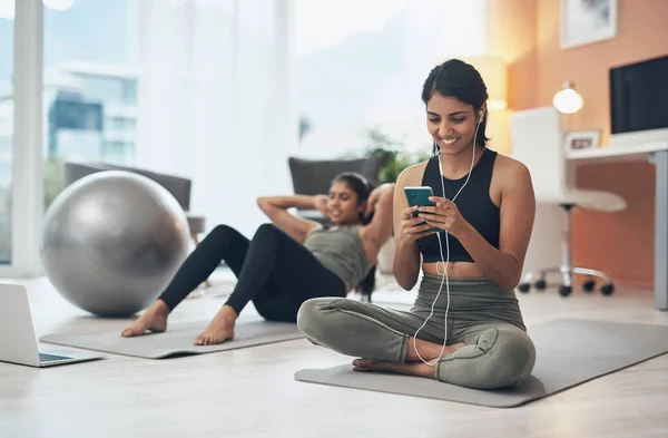 把节拍调大些 把你锻炼的强度调大些 在家锻炼时通过手机听音乐的女人 — 图库照片