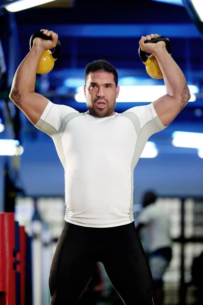 他的肌肉代表生意 一个在体育馆用水壶铃铛锻炼的男人 — 图库照片