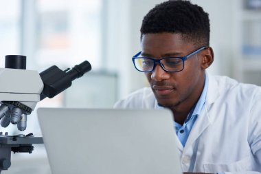 Bugün dikkatimi dağıtacak bir şey yok. Bir laboratuvarda otururken dizüstü bilgisayarı üzerinde çalışan odaklanmış genç bir bilim adamı.