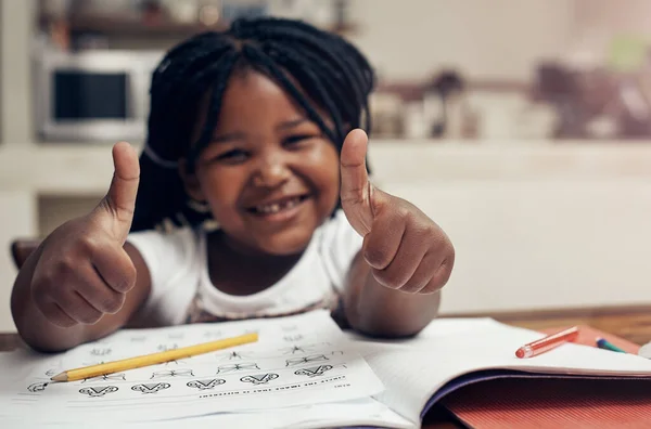 做作业很酷 一个可爱的小女孩在家里做作业时竖起大拇指摆姿势的画像 — 图库照片
