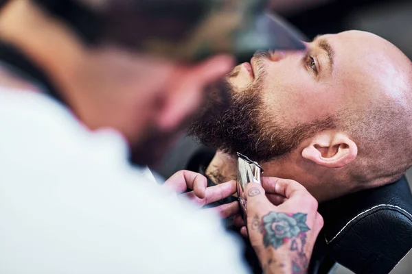 Working with beards is a delicate procedure. a handsome young man getting his beard trimmed and lined up at a barbershop