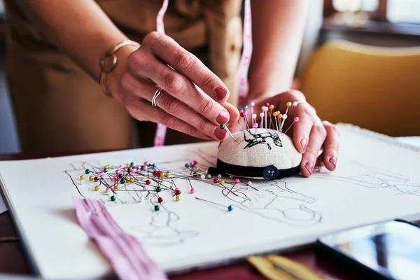 The fashion industry is full of color and creativity. an unrecognizable designer using a pincushion while working in her workshop