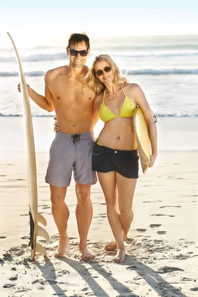 波を一緒に 筋肉質の若い男と彼の魅力的なガールフレンドの肖像画は ビーチでサーフボードを保持 — ストック写真
