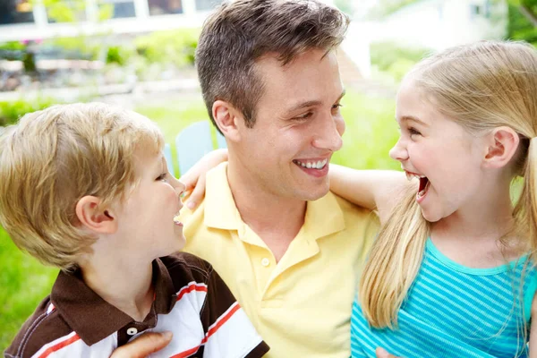 你真有趣 英俊的年轻父亲带着幸福的笑容抱着他的两个孩子 — 图库照片