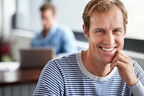 Happy to work here. Portrait of smiling man sitting in a casual work environment