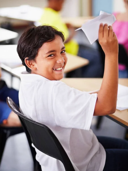肖像画 学生和纸飞机在教室里快乐 在课桌或印度男孩那里学习 玩折纸喷射机或课堂娱乐 开心的微笑 孩子和抱着飞机和初中的乐趣 — 图库照片