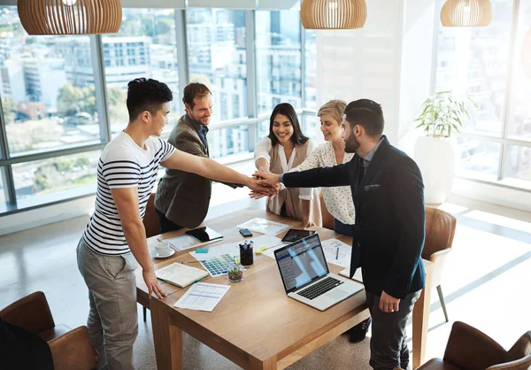 Together we can achieve greatness. a diverse group of businesspeople joining their hands in a huddle in an office