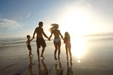 Gün batımının bir anını bile kaçırmadım. Gün batımında sahilde yürüyen genç bir ailenin dikiz görüntüsü.