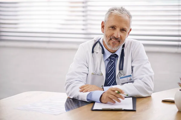 肖像和医生与剪贴板在他的办公室分析测试结果在医院 在诊所里坐在办公桌旁的自信 微笑和职业成熟的男性医务工作者 — 图库照片