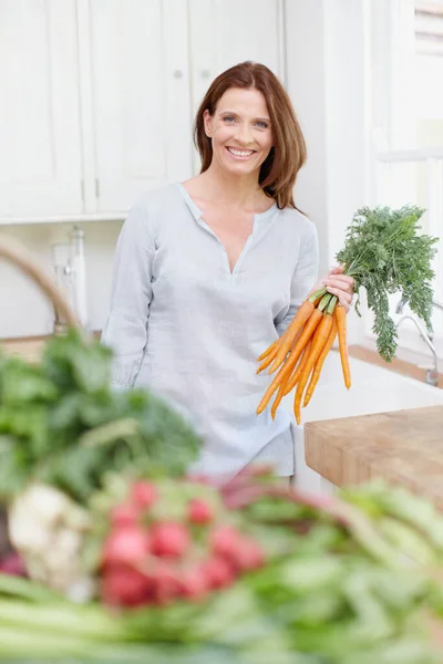Ylpeyteni Kaunis Nainen Seisoo Hänen Keittiössä Pitäen Joukko Porkkanoita — kuvapankkivalokuva
