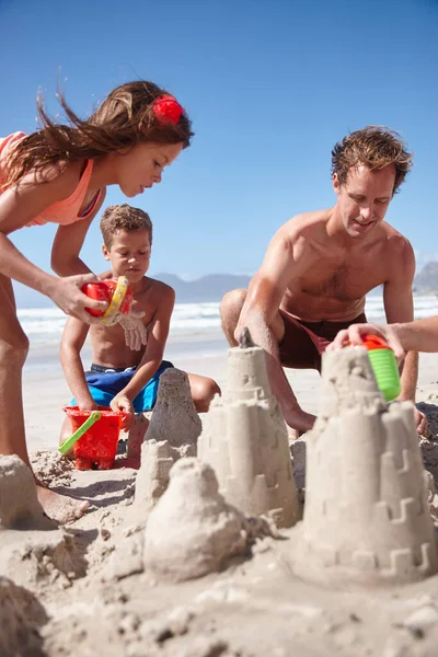 彼らの好きな形のビーチの楽しみ ビーチで一緒に砂の城を作る幸せな家族 — ストック写真