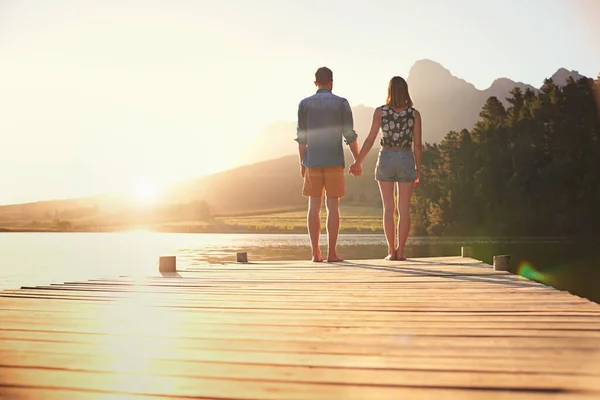 美しい夕日の下で愛 夕暮れ時にドックに立っている愛情のある若いカップルのレビューショット — ストック写真