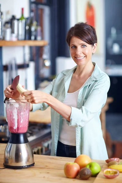 Now for her favorite ingredient...an attractive woman making a fruit smoothie in the kitchen
