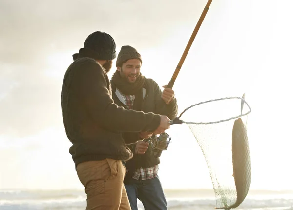抓住那个大的两个年轻人在海滩钓鱼 — 图库照片