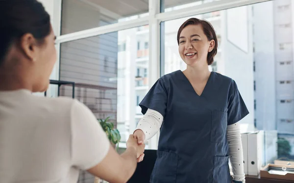 一个简单的握手可以创造一个如此巨大的连接 在办公室里与病人握手的年轻女医生 — 图库照片