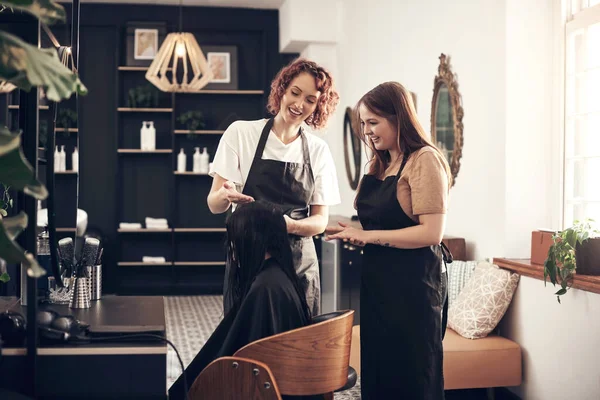 Stock image Find a salon that takes pride and care in the condition of your hair. two hairstylists looking at a clients hair together