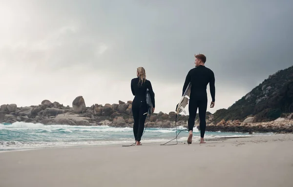 私達は同じ利益を共有する ビーチで一緒にサーフィンをしている若いカップルが — ストック写真