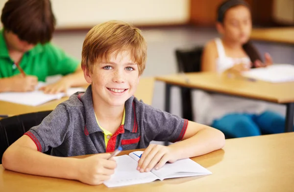 在一个儿童成长的教室里 一个学生坐在桌旁 他的肖像 教育和学习 在学校 孩子们和一个快乐的男孩一起写作 用笔记本学习 — 图库照片