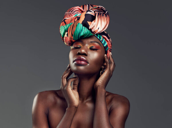 Beauty, makeup and black woman with a turban in studio with a elegant, glam and cosmetic face. Beautiful, young and African female model with a head wrap with sensual pose isolated by gray background.