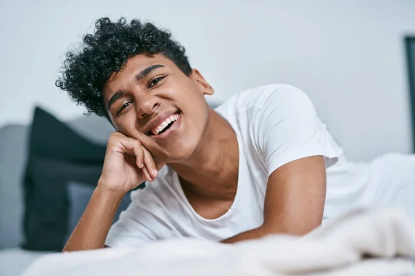更多的笑容 一个在家里床上休息的年轻人 — 图库照片