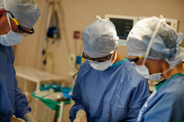 治疗是他们的使命 在手术室里进行外科手术的一组外科医生 — 图库照片