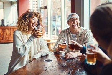 İndirimli içki saati hiç bu kadar mutlu olmamıştı. Bir grup arkadaş barda bira içiyorlar.