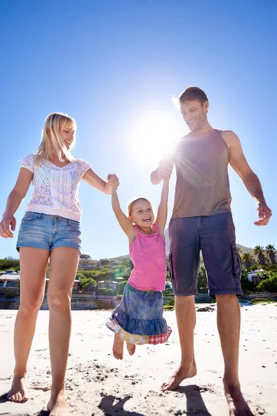 ビーチハウスを持つことの特典 ビーチを散歩している幸せな若い家族の完全な長さのショット — ストック写真