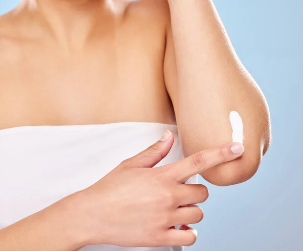 stock image Because dry skin isnt attractive at all. Studio shot of an unrecognisable woman applying lotion to her elbow against a blue background