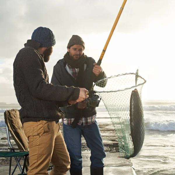 どれくらいの重さだと思う 2人の若い男が魚で桟橋から釣り — ストック写真