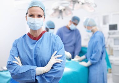 A caring profession. Portrait of a female doctor standing in an operating room wearing hosptial scrubs and gloves clipart