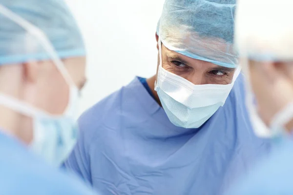 何年も手術を指揮してきた 手術室で仲間の外科医と手術をする男性外科医の作物のイメージ — ストック写真