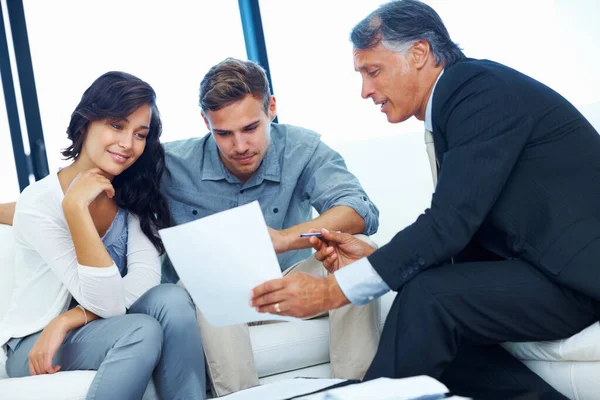 Financial planning. Mature financial advisor explaining financial plan to young couple at home