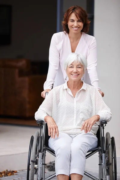 每一个积极的理由 一个把年迈的母亲推上轮椅的女人 — 图库照片