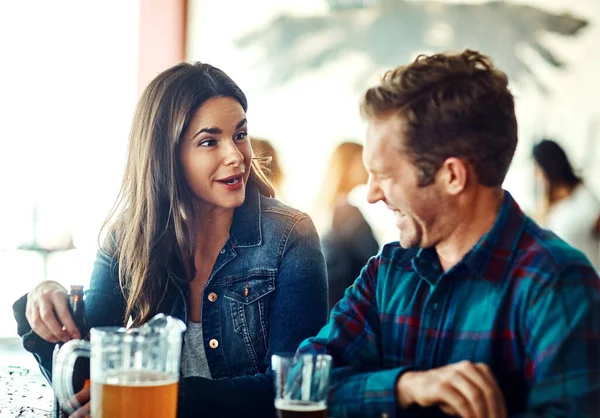 他喜欢她让他发笑的样子 一对年轻夫妇在酒吧里喝酒 — 图库照片