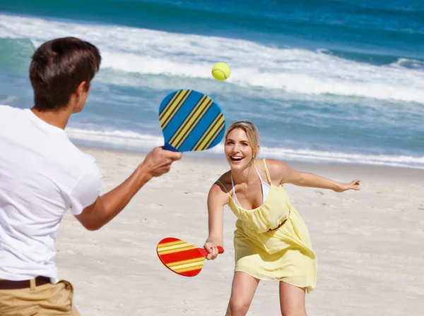 砂とパドルボール ビーチでパドルボールを楽しんでいる幸せな若いカップルは — ストック写真
