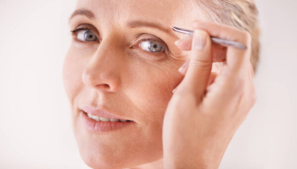 Perfect brows. Portrait of a beautiful mature woman plucking her eyebrows with a pair of tweezers