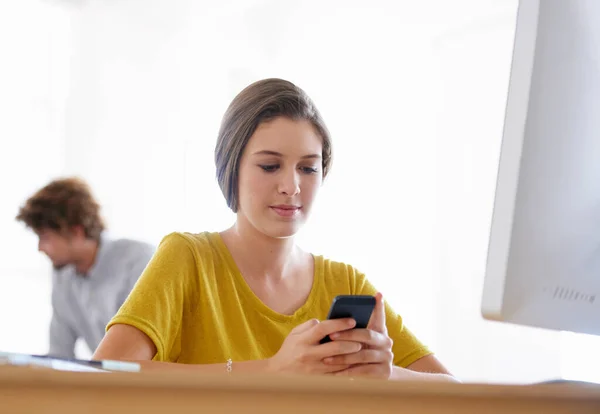 stock image Taking a moment to keep in touch. A beautiful young woman using her smartphone at the office