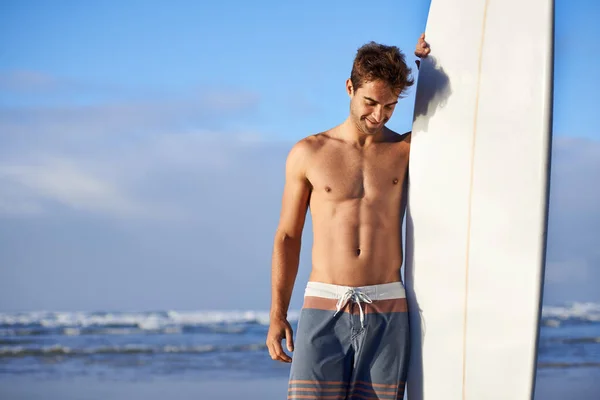 波を追いかけることが彼の情熱です 良い波を切望しているビーチでハンサムな若いサーファー — ストック写真