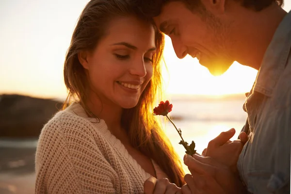 ビーチでの愛 幸せな若い女性に夕日のビーチで花を与える若い男 — ストック写真