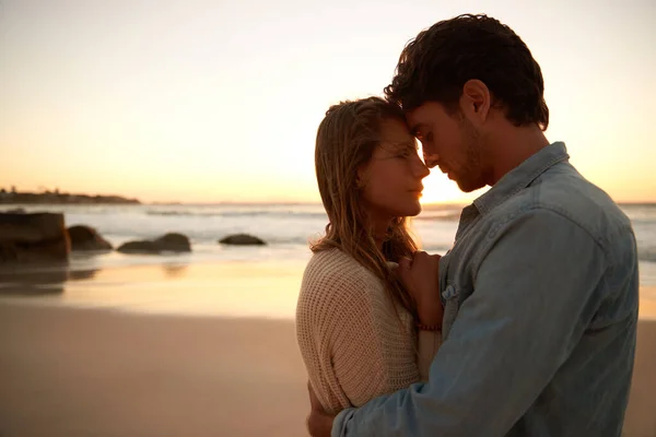 貴重な瞬間を共有する 日没時にビーチで抱き合っている若いカップルが — ストック写真